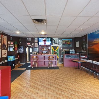 Inside Big Momma's: pink bar with stools, Jamaican flag, and tiled dining room